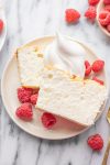 two slices of Jake's Cake on a plate, topped with whipped cream and fresh raspberries